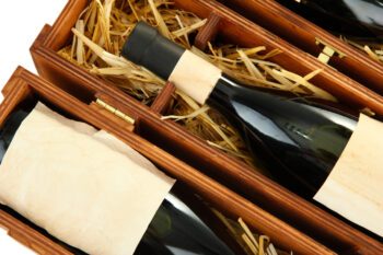 Bottles of old red wine in gift wooden box, isolated on white